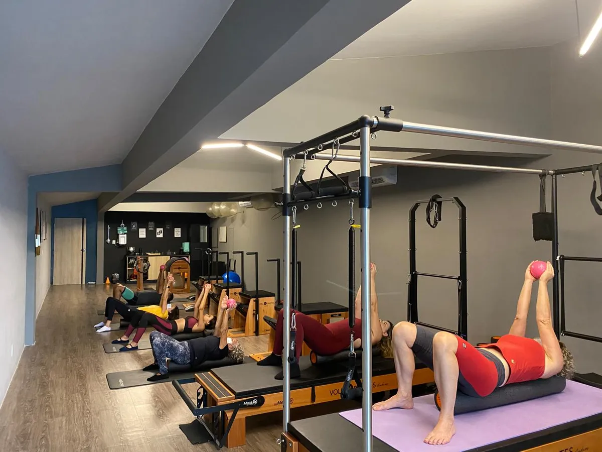 Aula em grupo no studio, com alunas deitadas nos equipamentos